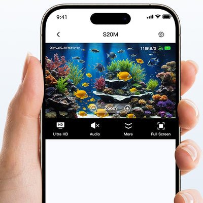 A hand holding a smartphone displaying a clear, colourful live view of a tropical aquarium on the screen.