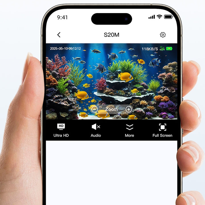 A hand holding a smartphone displaying a clear, colourful live view of a tropical aquarium on the screen.