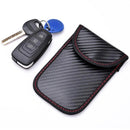Set of two black car keys with a blue key tag next to a black carbon-fibre pouch with red stitching.