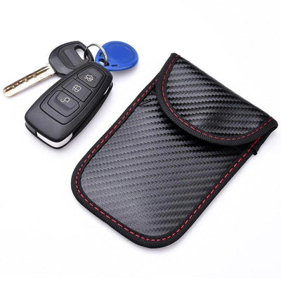 Set of two black car keys with a blue key tag next to a black carbon-fibre pouch with red stitching.